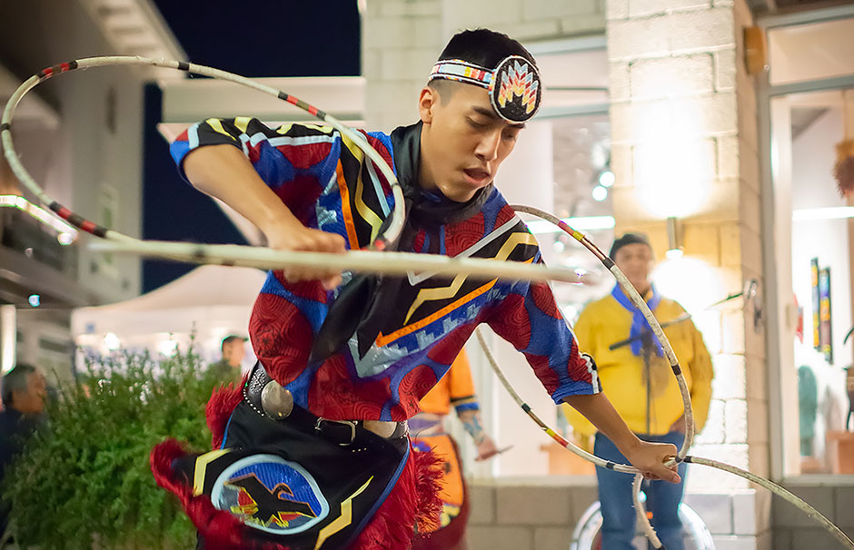 Native American hoop dancer performing in full regalia for onlookers