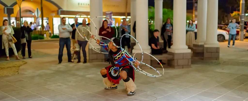 Hoop dancer Talon Duncan in traditional regalia strikes a dramatic pose with multiple hoops for ArtWalk visitors in Scottsdale, AZ.