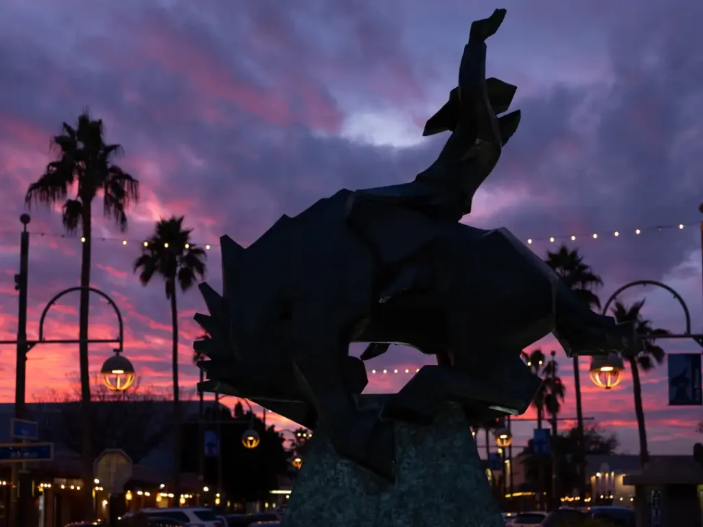 Silhouette of the Jack Knife sculpture in the center of Main Street in Old Town Scottsdale. The larger than life bronze sculpture depicts a cowboy riding a bucking bronco in a geometric, stylized form. 