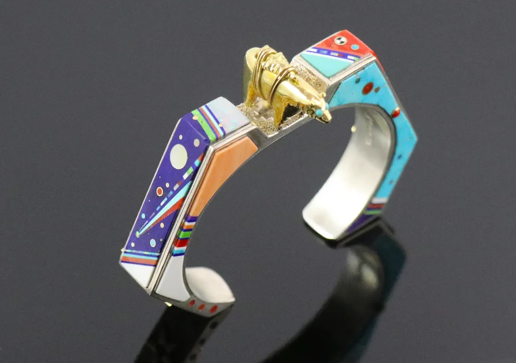 Hollow construction cuff bracelet with inlaid semi-precious marquetry stonework in night sky celestial patterns with a 3D gold bear fetish cast and placed at the center top.